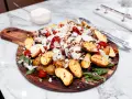 En härlig biff tagliata med rostade potatisklyftor, körsbärstomater och pinjenötter, toppad med parmesan.