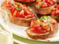 Krispiga bruschettor med färska tomater och basilika, perfekt för ett italienskt recept. Ett glas vitt vin till.