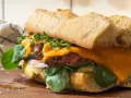 En saftig steak sandwich med smält ost, färska gröna blad och krispigt bröd.