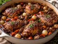 En mustig gryta med kycklinglår, champinjoner, små lökar och morötter i en mörk sås. En klassisk coq au vin som ser otroligt god ut.