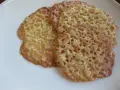 Tre gyllene, tunna havreflarn med ett vackert nätmönster ligger på en vit tallrik. Perfekt för ett enkelt havreflarn recept.
