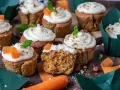 Fluffiga morotskaka muffins med krämig frosting, toppade med nötter och en liten morotsdekoration. Perfekta för fikat!