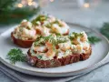 Två läckra skagen toast med räkor och dill på mörkt bröd, serverade på en tallrik.