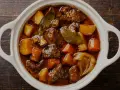 En vit gryta fylld med mustig boeuf bourguignon, med möra köttbitar, potatis och morötter. Perfekt vin till boeuf bourguignon.