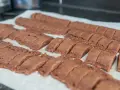 Chokladsnittar recept: Nybakade, mörka chokladkakor uppskurna i bitar på bakplåtspapper.