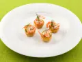 Fyra små, krispiga tempura rolls med räkor och dill på en vit tallrik.