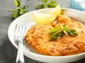 En gyllene schnitzel med citron och persilja, perfekt till ett glas vin.