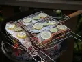 Grillad fisk med citron- och limeskivor på en kolgrill. Doften av sommar och god mat sprider sig.