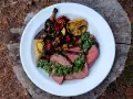 Skivat picanha på en tallrik med grillade grönsaker och citron. Perfekt för en somrig picanha grilla.