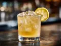 Ett glas med is och en citronskiva, en klassisk whiskey sour som väntar.