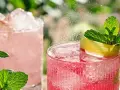 Två glas med rosa rabarbersaft utan att koka, is och mynta. Sprudlande och uppfriskande drycker för en varm sommardag.