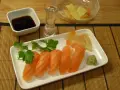 Njut av grillad lax sushi med wasabi, ingefära, sojasås och en shot sake.
