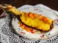 En saftig ananasskiva, toppad med kanderad frukt, serverad på en vacker tallrik. Ett konstverk som visar hur man kan dela ananas utan kniv.