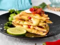 En stapel krispiga quesadillas med smält ost, jalapeños och salsa. Ett perfekt monterey jack ost alternativ för en smakrik måltid.
