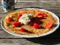 En stor pannkaka med vispad grädde, jordgubbar och sylt. Perfekt för ett enkelt pannkakor recept.