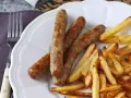 Saftig korv i airfryer med krispiga pommes frites på en vit tallrik. Enkel och god middag.