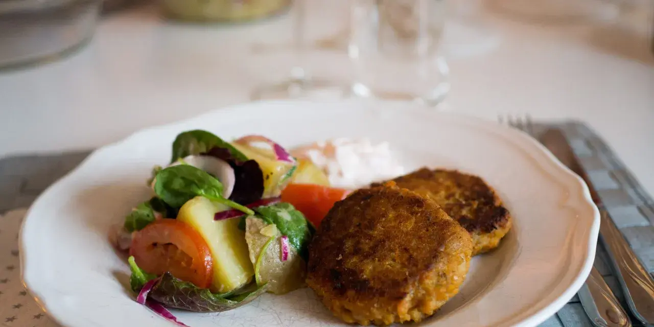 Två gyllenbruna biffar, troligen baserade på ett linser recept, serveras med en fräsch sallad och en klick sås.