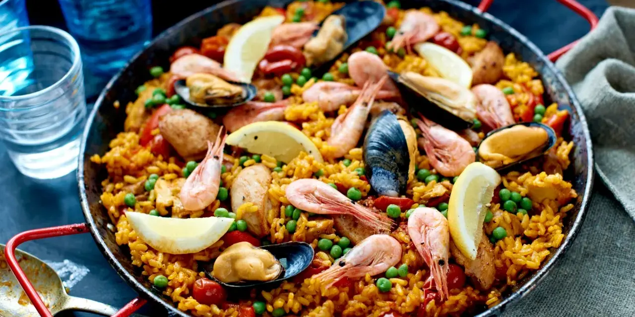 En stor paella med ris, räkor, musslor, gröna ärtor och citronklyftor. Perfekt vilket ris till paella som helst!