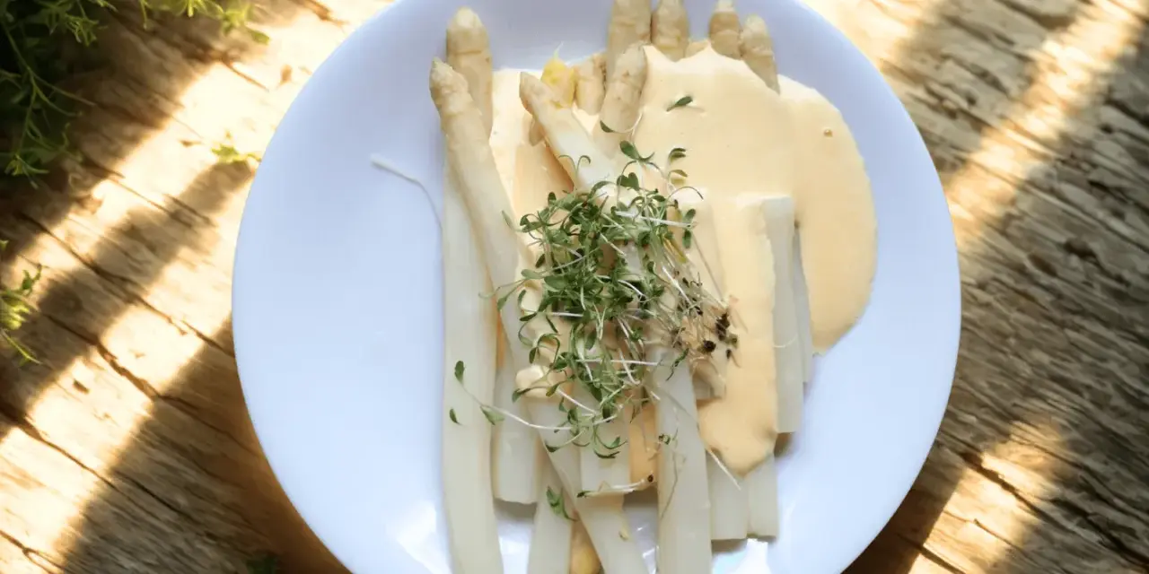 Vit sparris serverad med en krämig sås och toppad med färska groddar. En delikatess som smakar sommar.