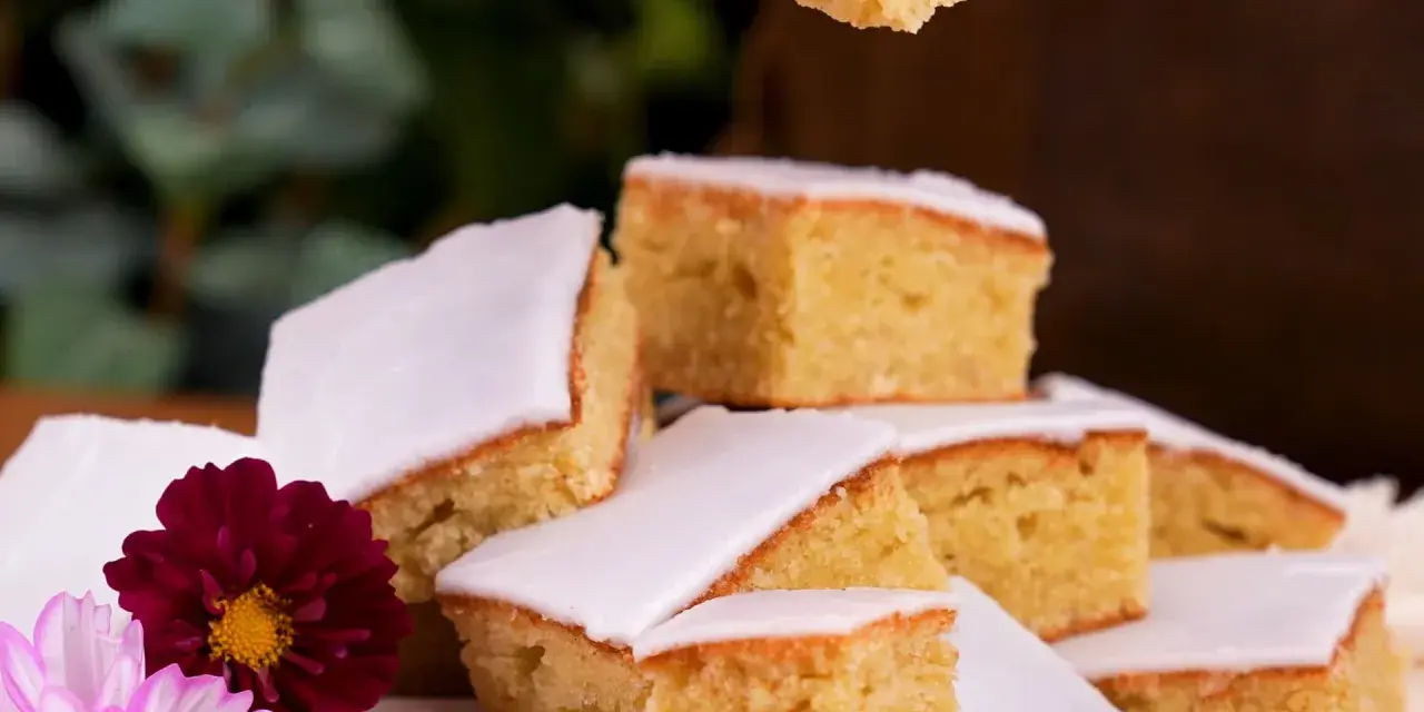 En härlig mazarinkaka i långpanna, skuren i bitar och dekorerad med blommor. En perfekt fika!