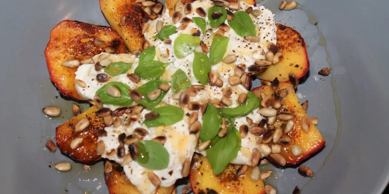 Grillad persika burrata med solrosfrön och basilika. En somrig rätt som smälter i munnen.
