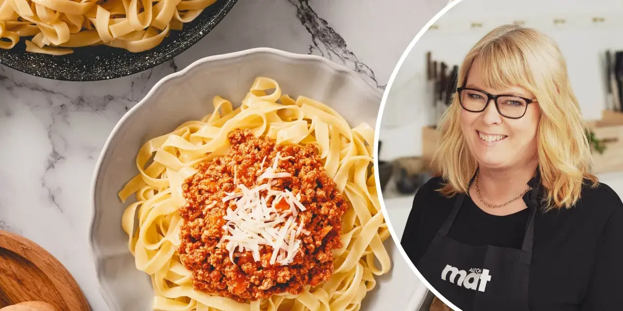 En kvinna med glasögon ler bredvid en skål med tagliatelle och köttfärssås. Perfekt för en snabb middag, den kokta pastan i kylen är redo att serveras.