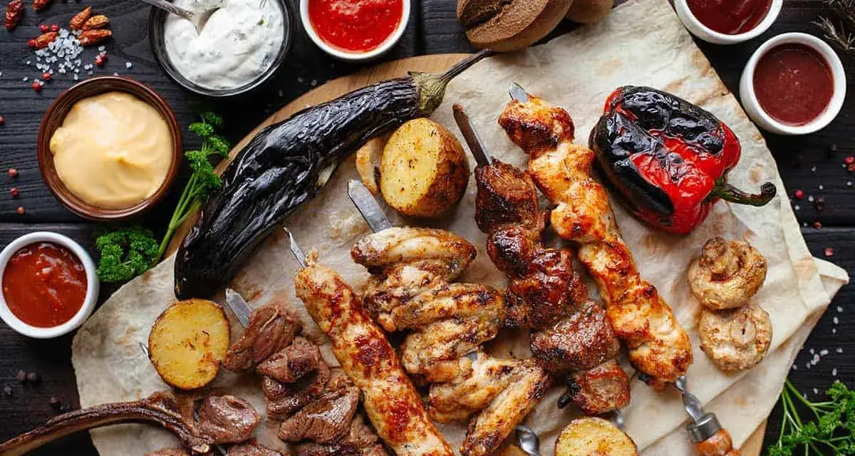En härlig grilltallrik med köttspett, kycklingvingar, grönsaker och såser. Perfekt vin till tagliata.