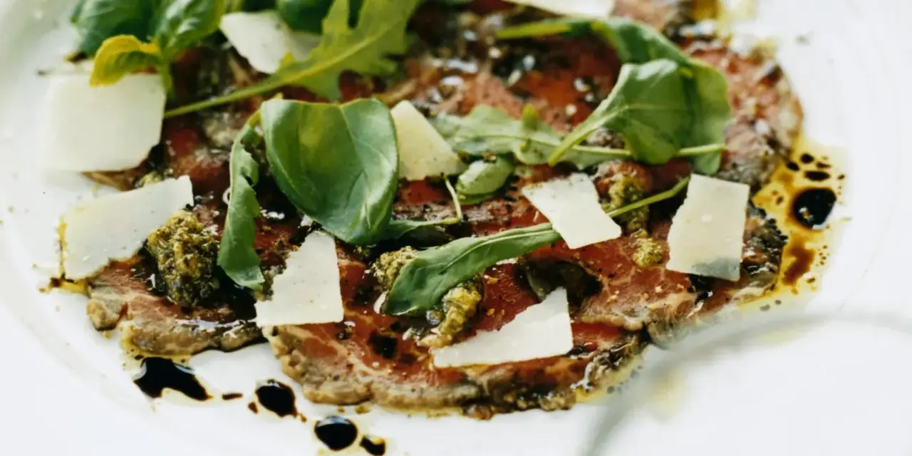 En läcker carpaccio med tunt skivad biff, parmesan, ruccola och pesto. Ett perfekt carpaccio recept för en fin middag.