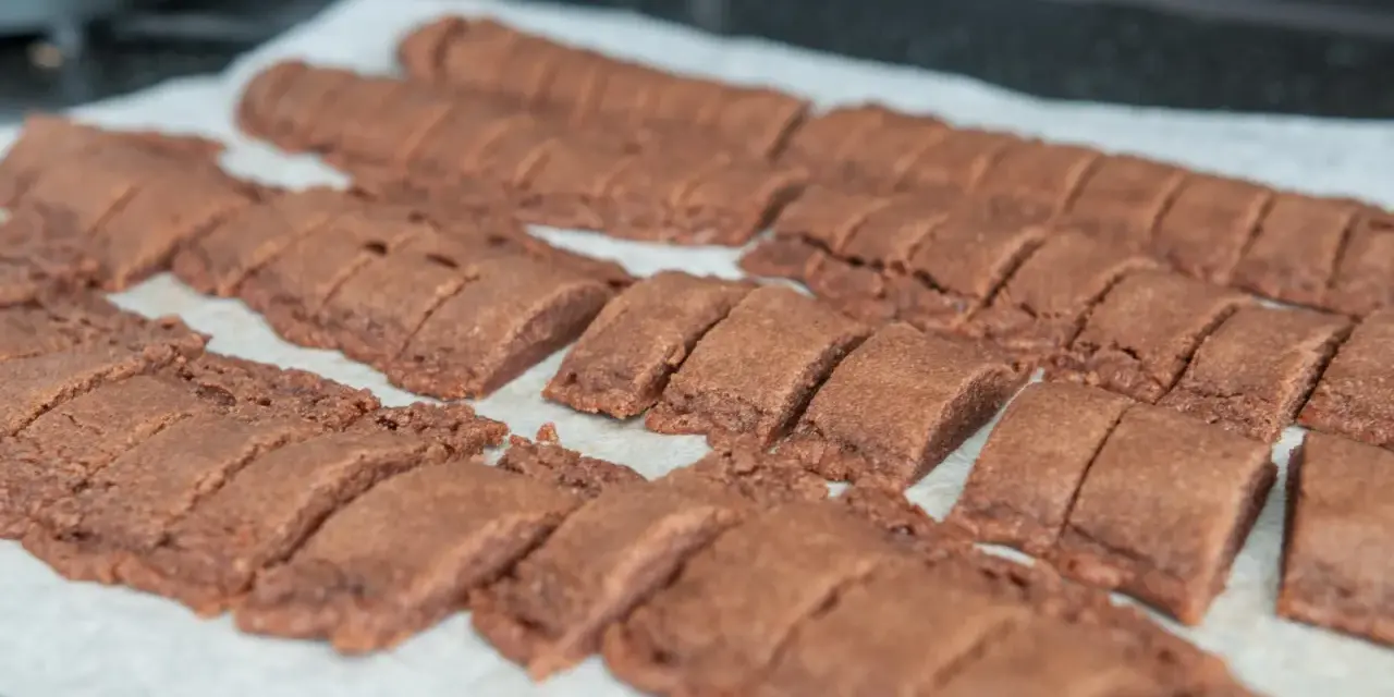 Chokladsnittar recept: Nybakade, mörka chokladkakor uppskurna i bitar på bakplåtspapper.