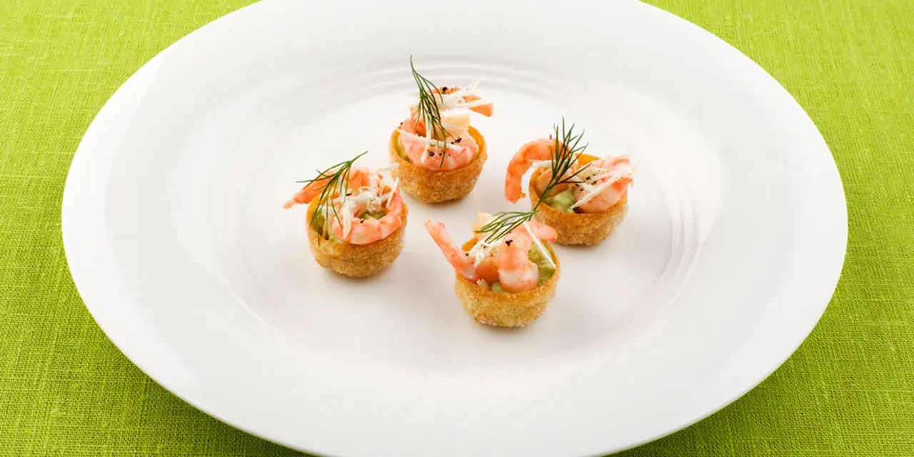 Fyra små, krispiga tempura rolls med räkor och dill på en vit tallrik.