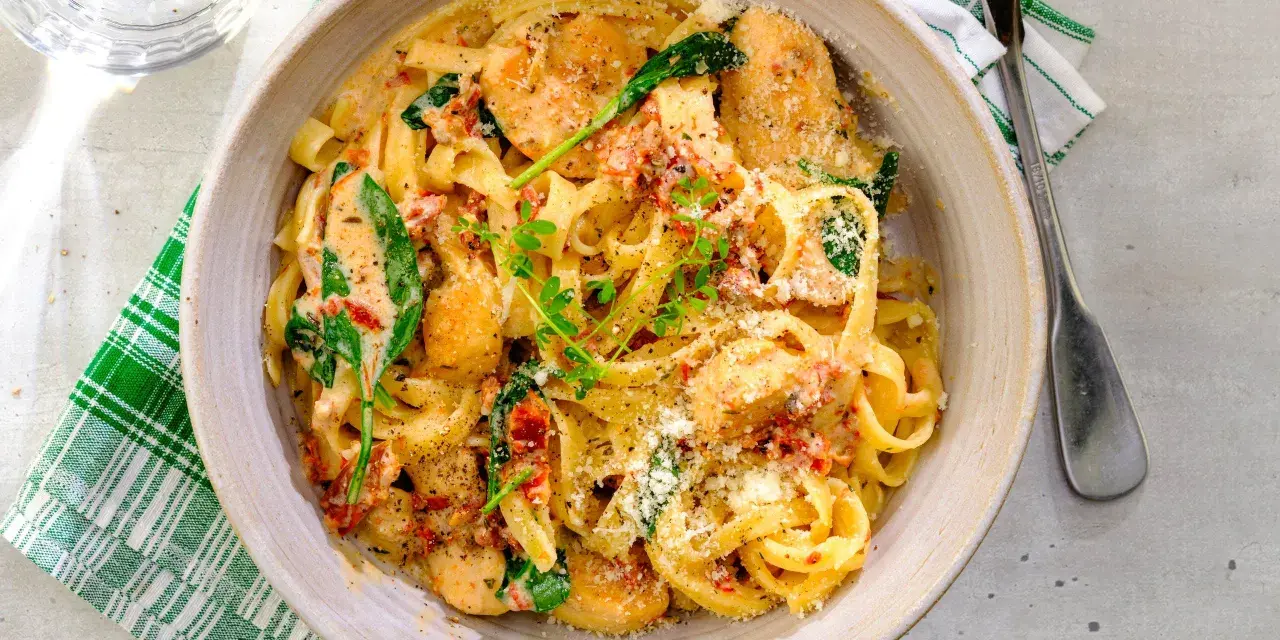 En krämig pastarätt med kyckling och soltorkade tomater, toppad med parmesan och färska örter.