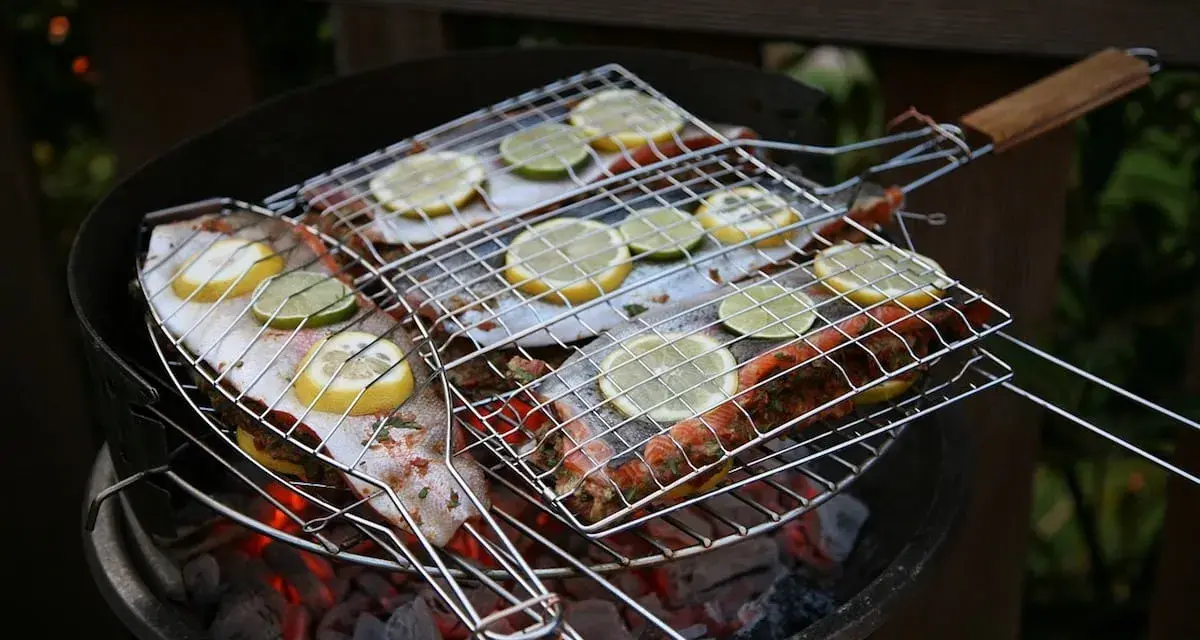 Grillad fisk med citron- och limeskivor på en kolgrill. Doften av sommar och god mat sprider sig.
