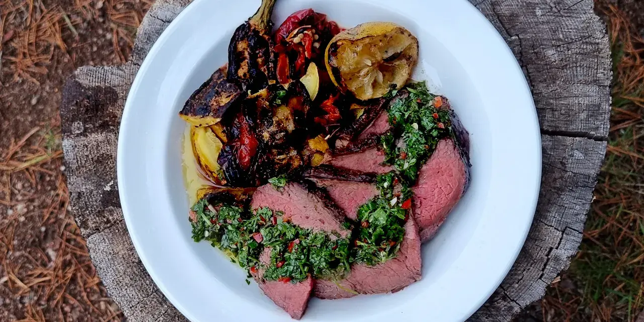 Skivat picanha på en tallrik med grillade grönsaker och citron. Perfekt för en somrig picanha grilla.