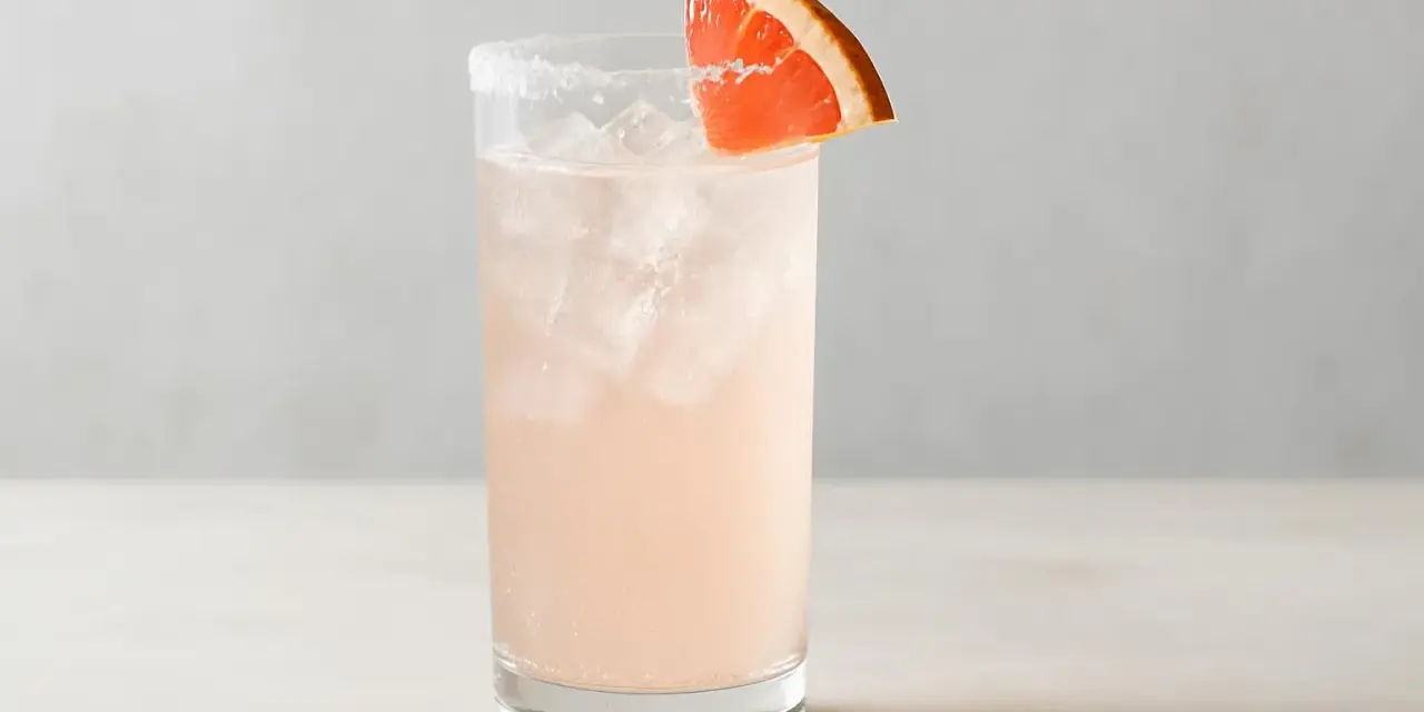 En uppfriskande Paloma drink med is och en grapefruktskiva som garnering.