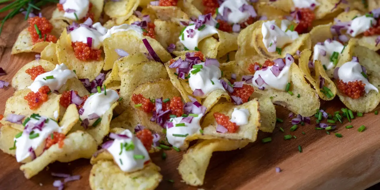 Krispiga chips med klickar av smetana, röd rom, finhackad rödlök och gräslök. En festlig förrätt!