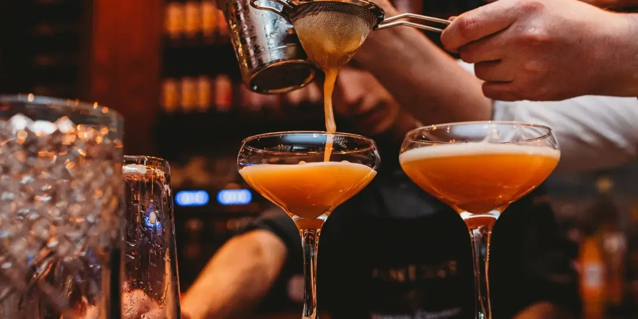En bartender häller upp en Pornstar Martini i ett elegant glas.