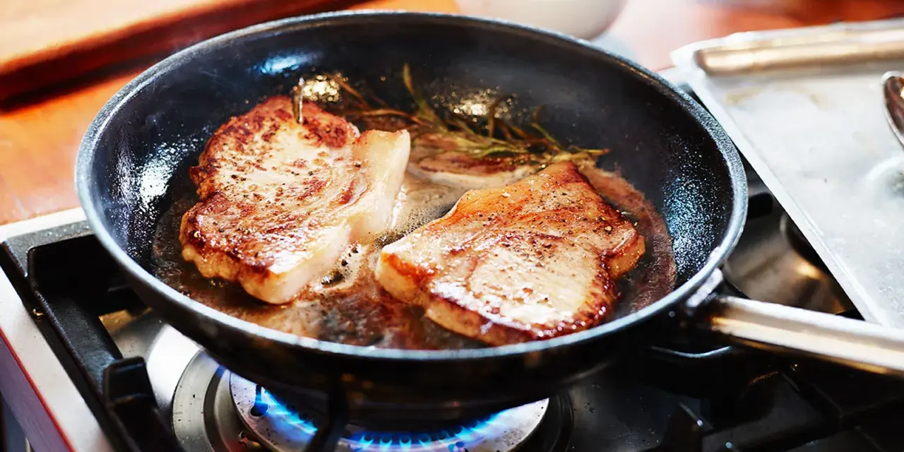 Två saftiga fläskkotletter steks i en panna med rosmarin. Ett perfekt karre recept för en god middag.