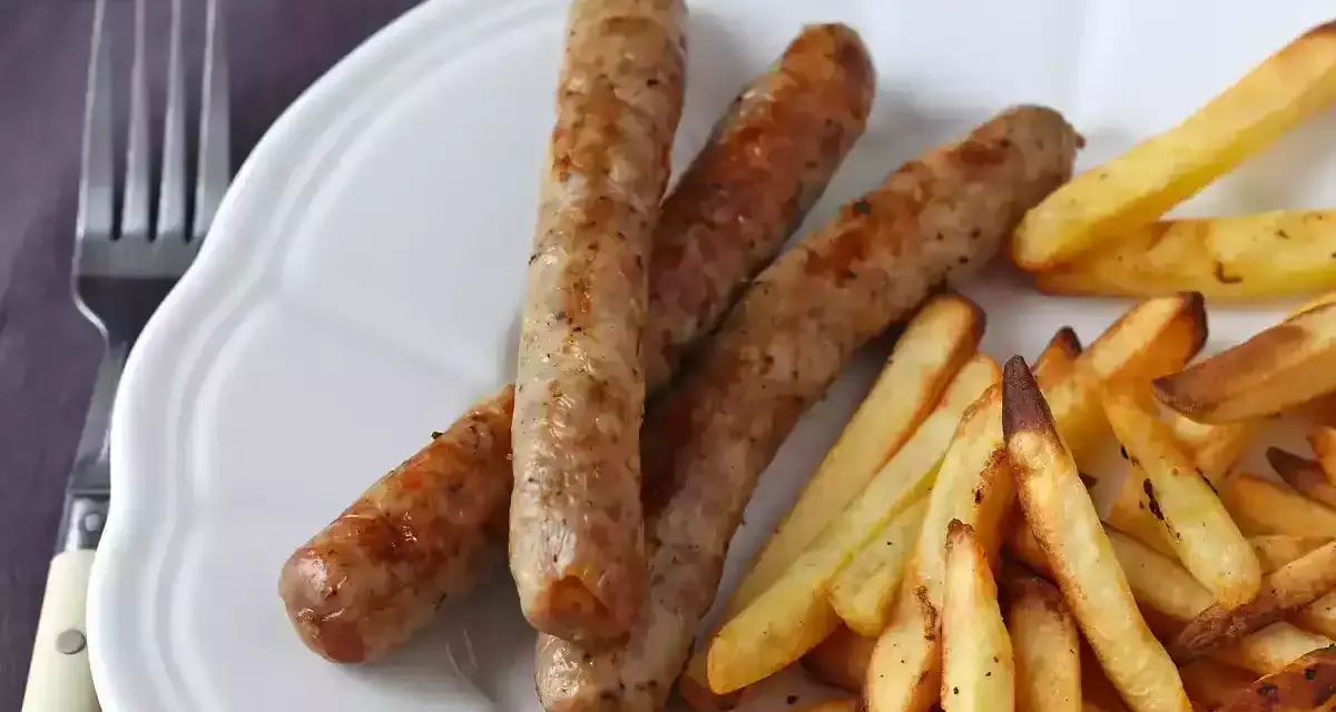 Saftig korv i airfryer med krispiga pommes frites på en vit tallrik. Enkel och god middag.