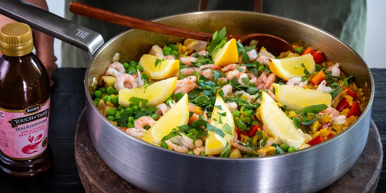 En härlig paella med räkor, ärtor och citronklyftor, perfekt för ett gott paella recept.