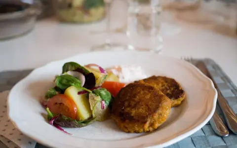 Två gyllenbruna biffar, troligen baserade på ett linser recept, serveras med en fräsch sallad och en klick sås.