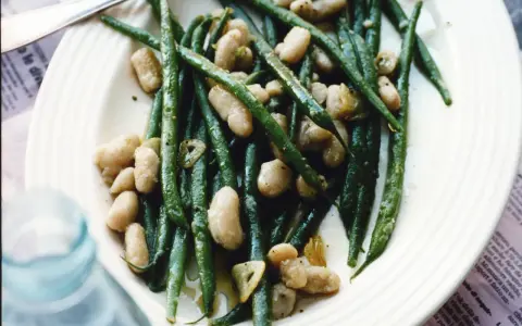 En tallrik med gröna haricots verts och vita bönor, lätt oljade och kryddade. En läcker och enkel rätt.