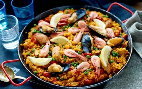 En stor paella med ris, räkor, musslor, gröna ärtor och citronklyftor. Perfekt vilket ris till paella som helst!