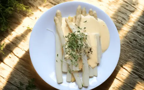 Vit sparris serverad med en krämig sås och toppad med färska groddar. En delikatess som smakar sommar.