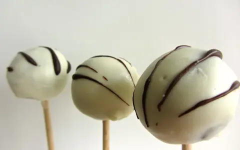 Tre vita cake pops med mörk chokladglasyr, perfekta för ett enkelt cake pops recept.