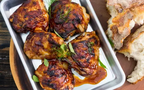 Saftiga kycklinglår med ben, glaserade och serverade med bröd. Ett perfekt kycklinglår med ben recept för middagen.
