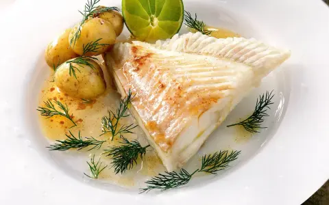 Piggvar i ugn serverad med småpotatis, dill och en limeklyfta. En delikat rätt som doftar hav.
