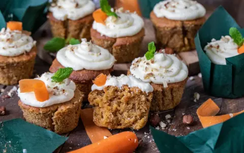 Fluffiga morotskaka muffins med krämig frosting, toppade med nötter och en liten morotsdekoration. Perfekta för fikat!