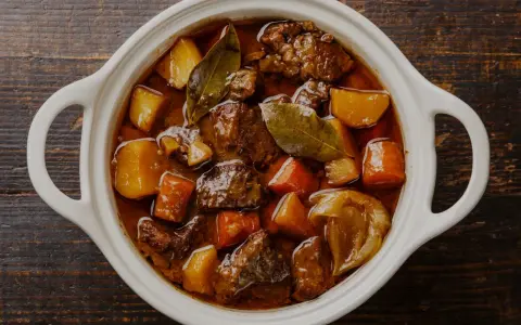 En vit gryta fylld med mustig boeuf bourguignon, med möra köttbitar, potatis och morötter. Perfekt vin till boeuf bourguignon.