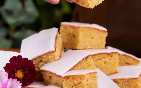 En härlig mazarinkaka i långpanna, skuren i bitar och dekorerad med blommor. En perfekt fika!