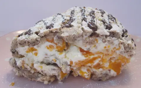 En bit av en Budapestrulle med aprikoser och grädde, toppad med choklad och florsocker. Ett härligt budapestrulle recept!